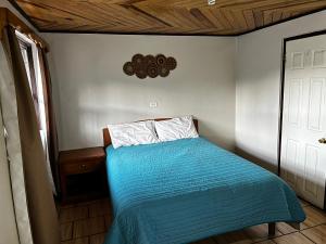 a small bedroom with a bed with a blue comforter at hotel Rarámuri in Creel
