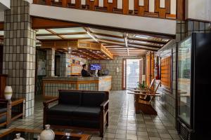 a lobby with a couch and a man in a kitchen at Shalako Hotel in Vitória da Conquista