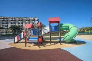 a playground with a green slide in a park at Holiday Apartment Patacona Beach in Valencia