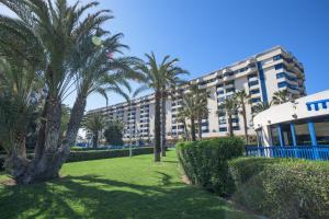 a large building with palm trees in a park at Holiday Apartment Patacona Beach in Valencia