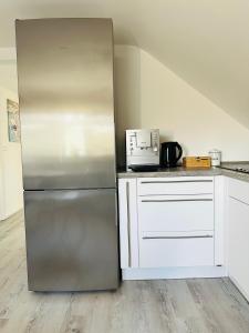 a stainless steel refrigerator in a kitchen with white cabinets at Stilvolles Apartment in Schweinfurt