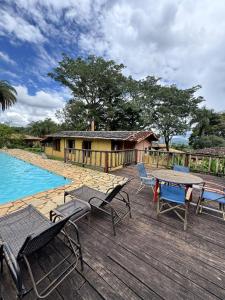 a deck with chairs and a table next to a pool at Capricho Asturiano in Santo Antônio do Leite