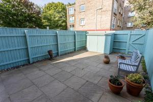 a patio with two chairs and a blue fence at Reel Time - Beautiful Townhouse a Stone's Throw from Poole Quay in Poole
