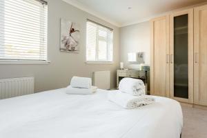 a bedroom with a large white bed with towels on it at Reel Time - Beautiful Townhouse a Stone's Throw from Poole Quay in Poole