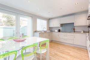 a kitchen with white cabinets and a table and chairs at Reel Time - Beautiful Townhouse a Stone's Throw from Poole Quay in Poole
