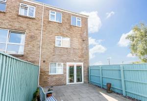 a brick building with a blue fence in front of it at Reel Time - Beautiful Townhouse a Stone's Throw from Poole Quay in Poole