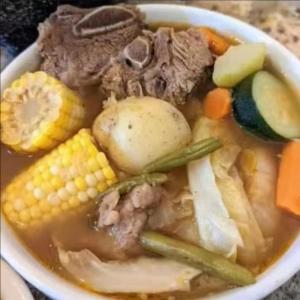 a bowl of soup with meat and vegetables on a table at Casa Shakira in Puerto Jiménez