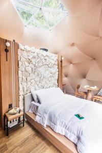 a bedroom with a large bed with a stone wall at Refúgio Bela Cabanas in Imaruí
