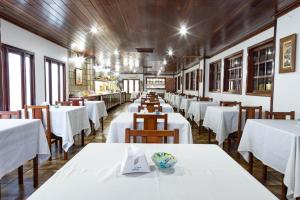 a dining room with white tables and wooden ceilings at Shalako Hotel in Vitória da Conquista