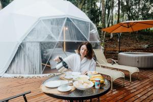 a woman pouring coffee on a table in a tent at Refúgio Bela Cabanas in Imaruí