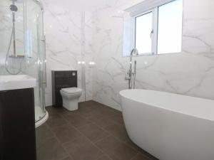a white bathroom with a tub and a toilet at Golygfa in Bodorgan +39 photos