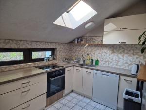 a kitchen with white cabinets and a skylight at Apartman Gradina in Doboj