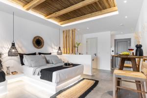 a white bedroom with a bed and a table at Naxos Anamnisi in Plaka