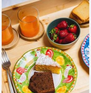 a table with a plate of cake and a bowl of strawberries at Rifugio Felice in Bagnolo Piemonte
