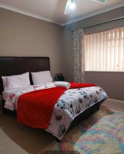 a bedroom with a bed with a red blanket and a window at Mestil Guesthouse in Hoheizen