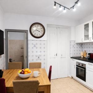 a kitchen with a table and a clock on the wall at Cascais Little Garden Rooms Old Town in Cascais