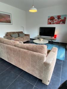 a living room with two couches and a tv at Woning met 4 slaapkamers in Zelzate