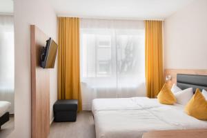 a hotel room with a bed and a television at Hotel Gute Hoffnung Pforzheim in Pforzheim