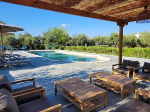 a patio with chairs and a swimming pool at Beachfront cottage house in olive grove in Arkitsa