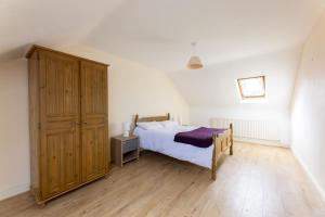a bedroom with a bed and a wooden cabinet at Ballyneill Farmhouse in Carrick-on-Suir