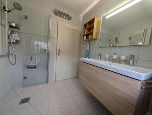 a bathroom with a sink and a shower and a mirror at Dreimädelshaus in Uhldingen-Mühlhofen +17 photos