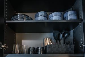 a shelf with plates and utensils in a kitchen at Kitz Alpine Apartments - City Center in Kitzbühel +7 photos