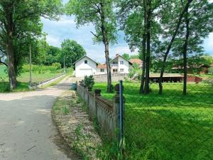 a fence in front of a field with a house at Imanje Mihailovic 3 in Pružatovac