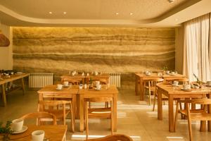 a restaurant with wooden tables and chairs and a wall at Howard Johnson Alcántara Boutique Hotel Chacras de Coria, Mendoza in Chacras de Coria