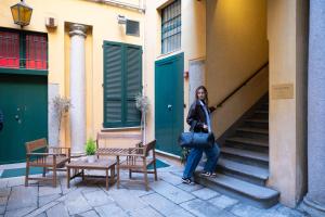 a woman sitting on a bench in front of a building at The Orso Suite -Brera in Milan
