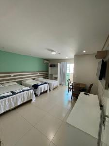 a hotel room with three beds and a table and chairs at Pousada Recanto Armação in Penha