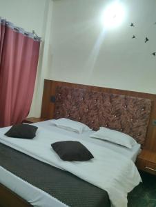 a large bed with black and white pillows on it at Nanda devi hotel in Mussoorie