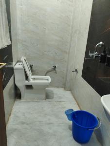 a bathroom with a toilet and a blue bucket at Nanda devi hotel in Mussoorie +5 photos