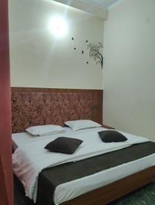 a bedroom with a large bed with black pillows at Nanda devi hotel in Mussoorie