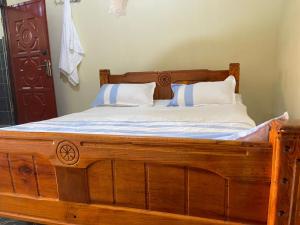 a wooden bed with two pillows on top of it at Solace Bar and Guest House in Kalangala