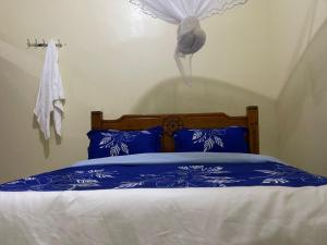 a bed with blue and white sheets and a bird on the wall at Solace Bar and Guest House in Kalangala