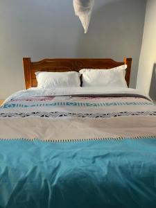 a bed with white pillows and blue sheets at Solace Bar and Guest House in Kalangala