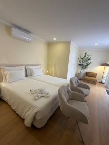 a bedroom with a large bed and two chairs at Inn & Art Madeira in Caniço