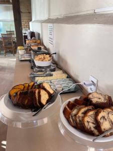 a buffet line with different types of bread and pastries at Pousada Recanto Armação in Penha