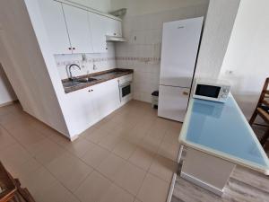 a kitchen with white cabinets and a sink and a refrigerator at brisa in Bajamar