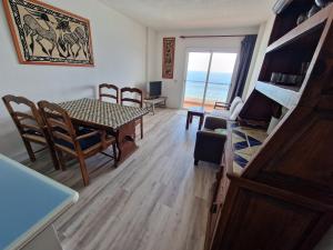 a living room with a table and chairs and the ocean at brisa in Bajamar