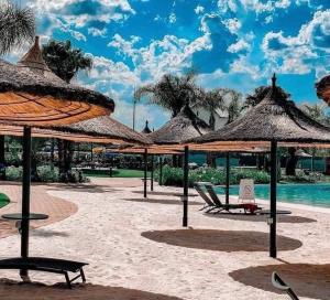 a beach with straw umbrellas and chairs and a pool at Lagoon escape Apartment in Pretoria