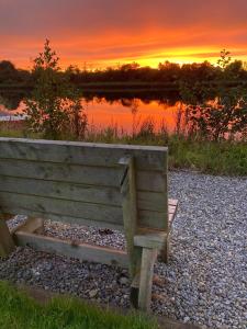 a wooden bench sitting on the rocks near a lake at Quiet Riverside Stopover by the Shannon in Leitrim