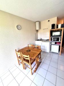 a kitchen with a wooden table and two chairs at Gîte La Vallée RDC Neyrac-les-Bains in Meyras