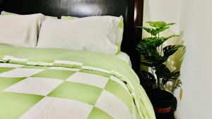 a bed with a green and white comforter and a plant at Joshiehome in Rancho Cucamonga
