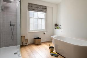 a bathroom with a white tub and a window at Tides Door in Dartmouth +23 photos