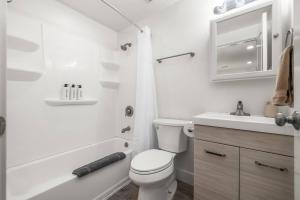 a white bathroom with a toilet and a sink at Cozy Orem House - Playground - Game Rm - Bunk Rm in Orem +24 photos