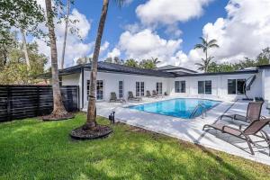 a swimming pool in the backyard of a house with palm trees at Guest Fav | 5BR Pool Estate | Sleeps 16 in Palmetto Bay