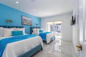 two beds in a room with blue walls at Guest Fav | 5BR Pool Estate | Sleeps 16 in Palmetto Bay +24 photos
