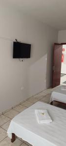 a room with two beds and a flat screen tv on the wall at Fazio Hotel in Jales
