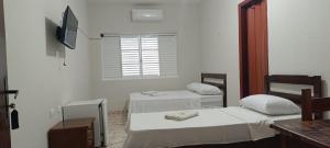a room with two beds and a television in it at Fazio Hotel in Jales